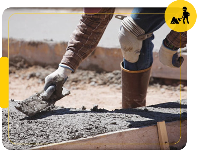 A person in white gloves and blue work boots is working on concrete.