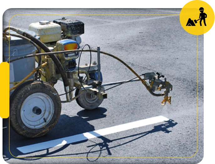 A man is using an air powered sprayer to spray paint the street.