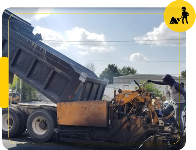 A dump truck is dumping trash on the side of the road.