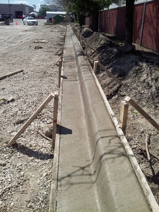 A concrete trench with pipes and wood supports.