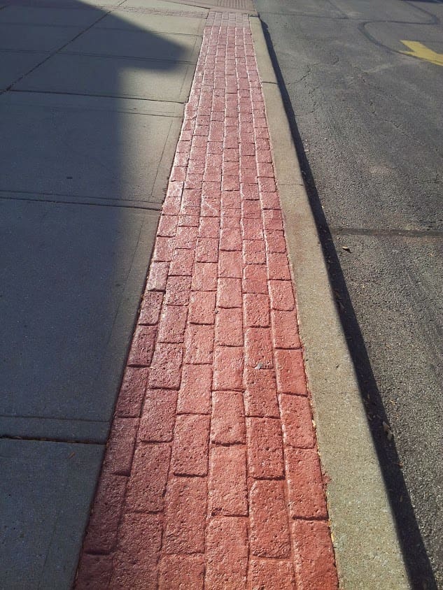 A brick sidewalk with red bricks on the side.