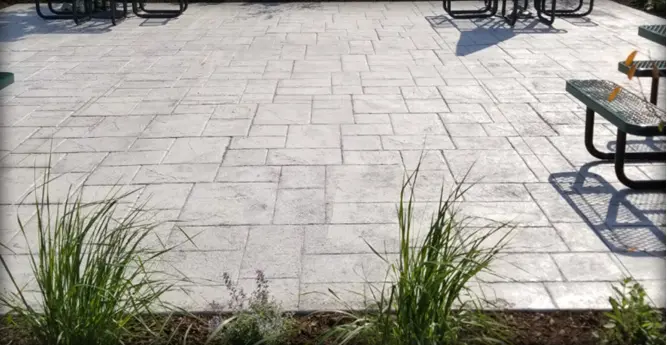 A stone patio with grass growing in the middle.