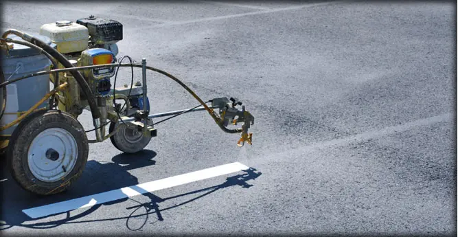 A person is using an air compressor to paint the street.