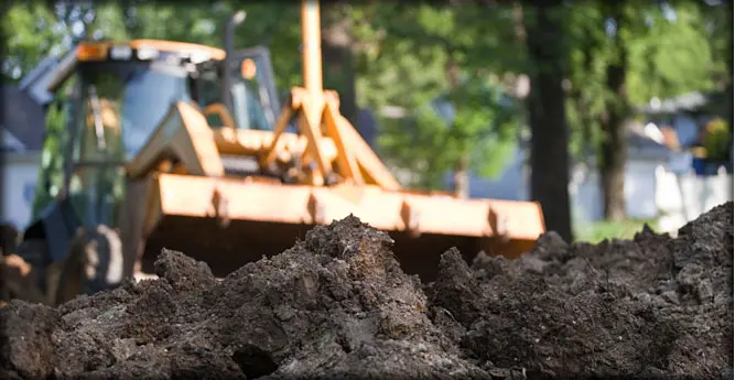 A tractor is parked in the background of a pile of dirt.